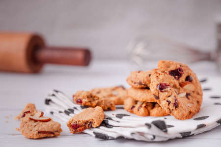 Piles of delicious chocolate chip cookies on a white plate with a milk bottle. Pastry utensils with white linen napkins on a wooden table. Delicious on a white plate with a bottle of milk.の写真素材