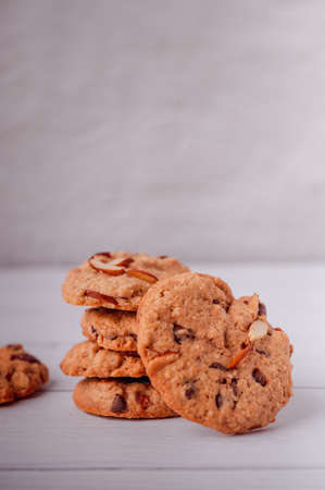 Piles of delicious chocolate chip cookies on a white plate with a milk bottle. Pastry utensils with white linen napkins on a wooden table. Delicious on a white plate with a bottle of milk.の写真素材