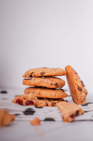 Piles of delicious chocolate chip cookies on a white plate with a milk bottle. Pastry utensils with...