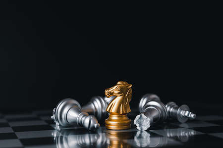 Gold king winner surrounded with silver chess pieces on chess board game competition.concept strategy, leadership and success business.の写真素材