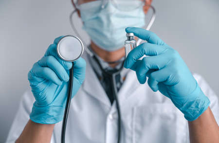 Doctors wear a surgical mask and glasses, Scientists hold syringes and vaccines for COVID-19. vaccination and laboratory experiments. Virus protection concept COVID-19.の写真素材