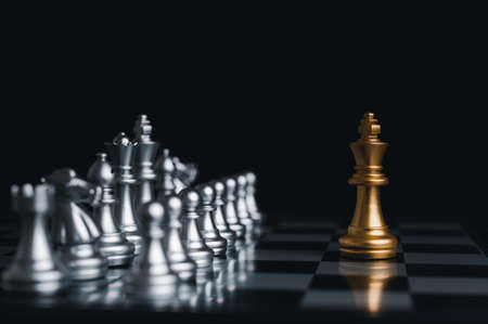Gold king winner surrounded with silver chess pieces on chess board game competition.concept strategy, leadership and success business.の写真素材