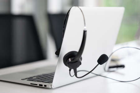 Headsets for call center teams are placed at a desk with a computer and laptop. while the team is in the breakの写真素材