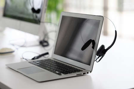 Headsets for call center teams are placed at a desk with a computer and laptop. while the team is in the breakの写真素材