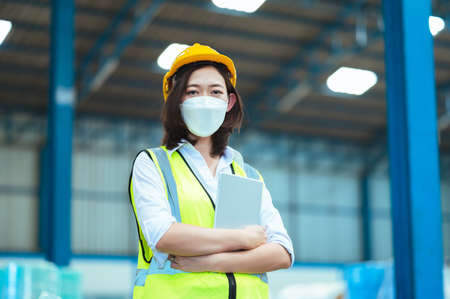 Chief industrial engineer inspects the mask factory. portrait woman while using a laptop. They show an assertive demeanor. Protective equipment in the danger zone.の写真素材