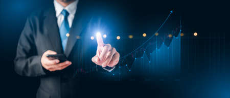 Businessman hand show Stock chart showing rising stock sign with graph indicator. Interest rate financial and mortgage rates concept. Double Exposure Image. Blue technology background high tech.の写真素材