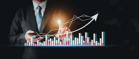 Businessman hand show Stock chart showing rising stock sign with graph indicator. Interest rate financial and mortgage rates concept. Double Exposure Image. Blue technology background high tech.の写真素材
