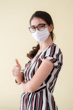 Young women wearing masks standing show plaster bandage at shoulder, do hand press like. After vaccine protection coronavirus 19 for immunization. Concepts prevent the spread of COVID-19.の写真素材