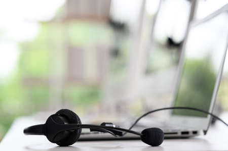 Headsets for call center teams are placed at a desk with a computer and laptop. while the team is in the breakの写真素材