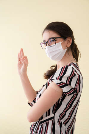 Young women wearing masks standing show plaster bandage at the shoulder make a mark hand sign OK.の写真素材