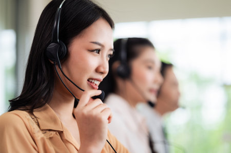 Team of call center staff in Asia wears headphones with a microphone. Smile while serving customers...