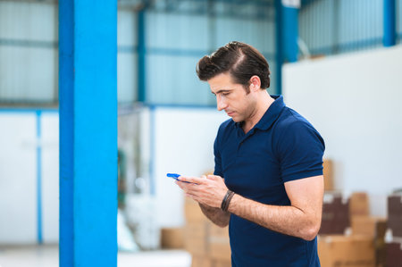 Management team, engineer, or foreman. Standing checking job information about industrial production management within the factory by phone. Teamwork concept.の写真素材