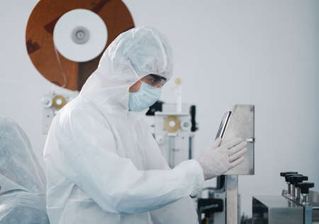 Scientists wearing protective clothing Inspect mask making machines in a laboratory at an industrial plant. Anti-virus production warehouse. concept of safety and prevention coronavirus covid-19.の写真素材