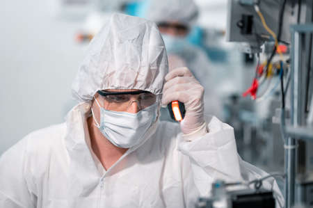 Scientists wearing protective clothing Inspect mask making machines in a laboratory at an industrial plant. Anti-virus production warehouse. concept of safety and prevention coronavirus covid-19.の写真素材