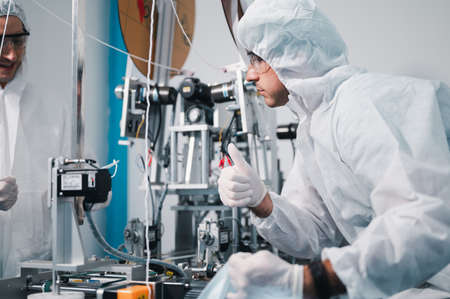 Two scientists wearing uniform protection. Check the manufacturing process face masks. With machinery in a laboratory at industry plants. The concept for security and protection coronavirus covid-19.の写真素材