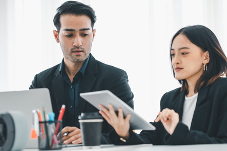 Businesswoman discussing charts and graphs showing on tablet screen with friend with smiling faces in the meeting room. Brainstorming and teamwork concept.の写真素材
