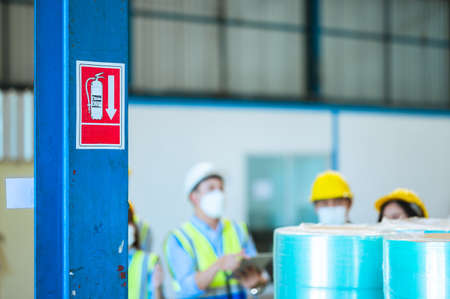 Team engineers and foreman wear a mask, hard hat, and vest. Standing consult discuss industrial production management. Explaining job details through laptops and tablets in factories or warehouses.の写真素材