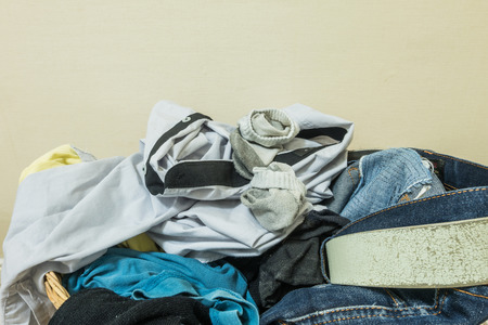 Closeup used clothes in wood basket at corner in roomの写真素材