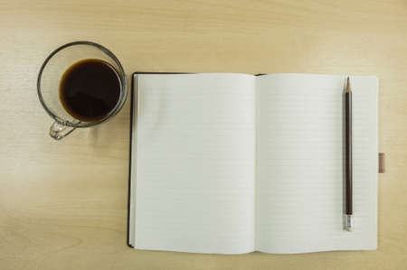 Brown note book , pencil and black coffee in work conceptの写真素材