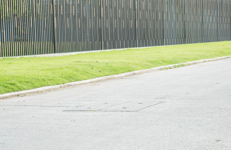 Beautiful fence with green grass and street at the park texture backgroundの写真素材