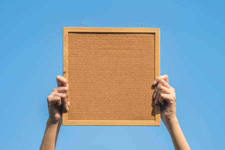Closeup cork board in hand of woman with sun lightの写真素材