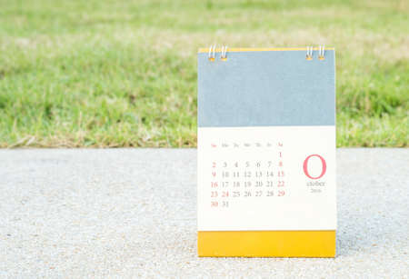 Closeup cute calendar in october on blurred stone floor and green grass in the garden view in the evening backgroundの写真素材