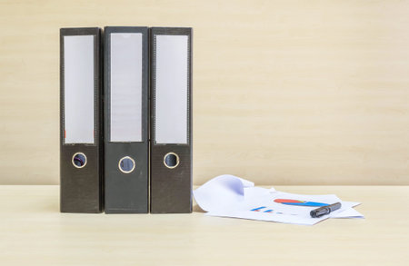 Closeup document file and work paper on blurred wooden desk and wall textured background in the...