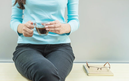 Asian woman rest for drink coffee in transparent glass cup in her hand in her free time in the room...