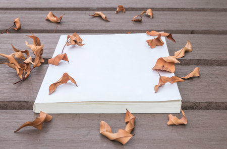 Closeup white note book on wooden table in the garden with dried leaves textured background
