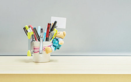 Closeup office equipment and color pen in desk tidy cup for pen on blurred wooden desk and frosted...