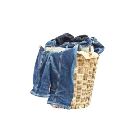 Closeup wood weave basket for used clothes with pile of clothes in house isolated on white backgroundの写真素材