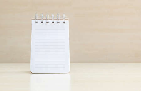 Closeup surface space at page of note book with line on blurred brown wood desk and wood wall textured background with copy space under window lightの写真素材