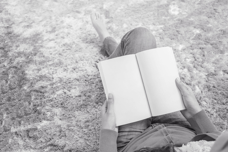 Closeup asian woman sitting on gray carpet at floor in the house textured background for read a book in relax time , free time at house concept in black and white toneの写真素材
