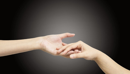 Closeup woman hand hold another woman hand for console and encourage in tender emotion isolated on black backgroundの写真素材