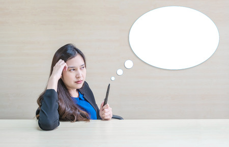 Closeup asian woman working with thinking face and pencil in her hand on blurred wooden desk and wooden wall textured background in meeting room , working woman with thinking concept with text boxの写真素材