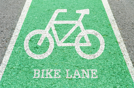 Closeup white painted of bicycle sign in green bike lane at the street floor in park textured backgroundの写真素材