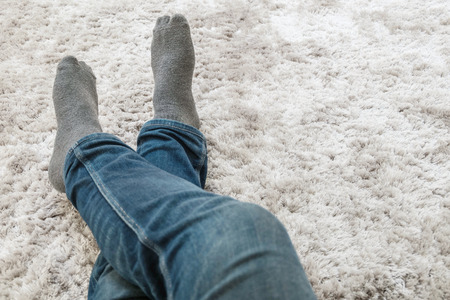 Closeup foot of man sit on gray carpet floor in house textured background with copy spaceの写真素材