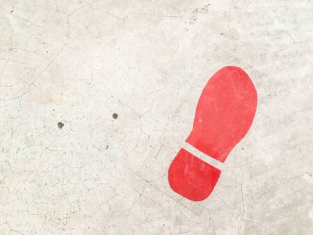 Closeup surface red footprint sign at dirty cement floor textured background with copy spaceの写真素材