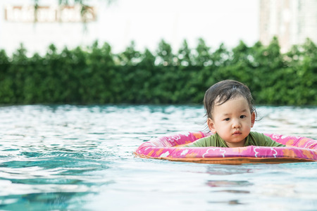 Closeup a baby boy sit in a boat for children in the swimming pool backgroundの写真素材