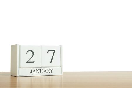 Closeup surface white wooden calendar with black 27 january word on blurred brown wood desk isolated on white background with copy space , selective focus at the calendarの写真素材