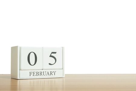 Closeup surface white wooden calendar with black 5 february word on blurred brown wood desk isolated on white background with copy space , selective focus at the calendarの写真素材