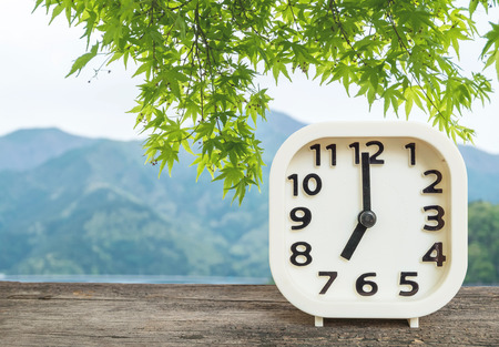 Closeup white clock for decorate in 7 o'clock on blurred mountain view backgroundの写真素材