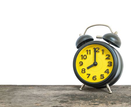 Closeup black and yellow alarm clock for decorate in 8 o'clock on old brown wood desk isolated on white background with copy spaceの写真素材