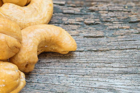 Closeup fried cashew nut on old wood desk textured backgroundの写真素材