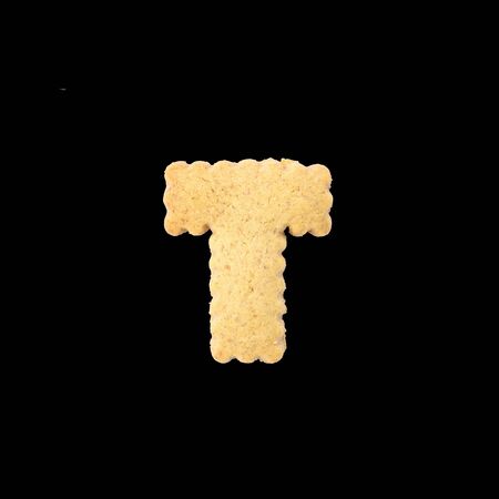 Closeup brown biscuit in T english alphabet isolated on black background with clipping pathの写真素材