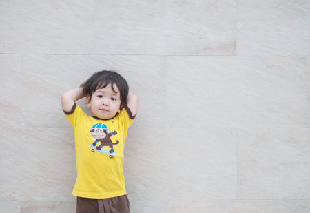 Closeup cute asian kid standing poses on marble stone wall textured background with copy space