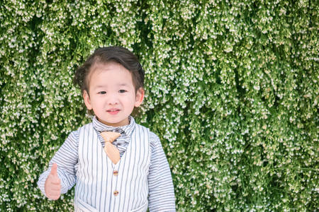 Closeup happy asian kid with admire motion on plant backdrop wedding textured background with copy spaceの写真素材