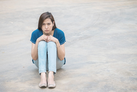Asian woman with sad face emotion on blurred concrete floor texture backgroundの写真素材