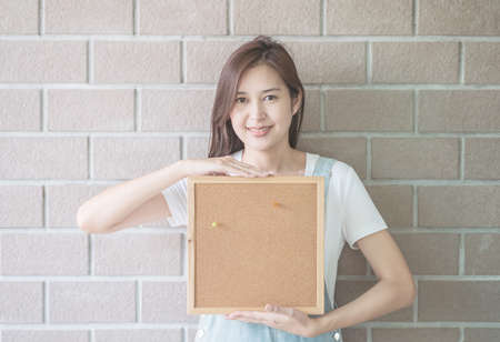 Asian woman with cork board in hand with smiling faceの写真素材