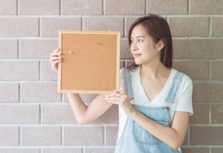 Asian woman with cork board in hand with smiling faceの写真素材
